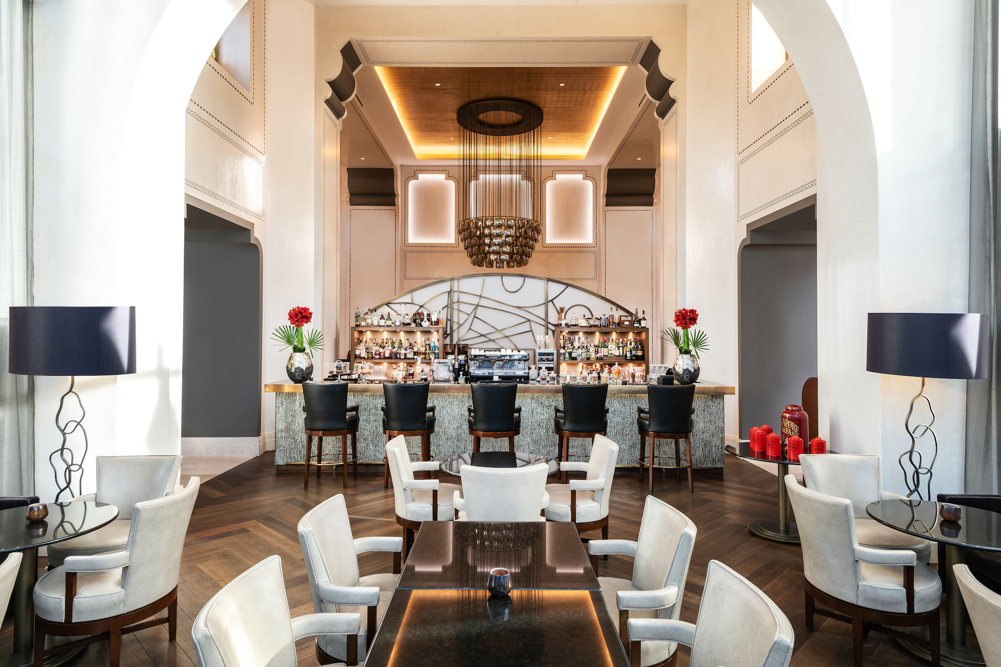 Elegant hotel bar with arches, soft beige tones, and chic furnishings, creates a welcoming, sophisticated atmosphere for guests.