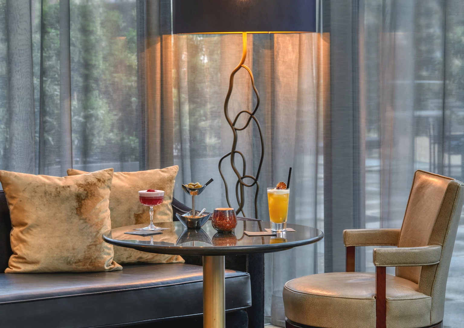 Cozy hotel lounge with plush seating and elegant drinks on a glass table, evoking a relaxing and sophisticated atmosphere.