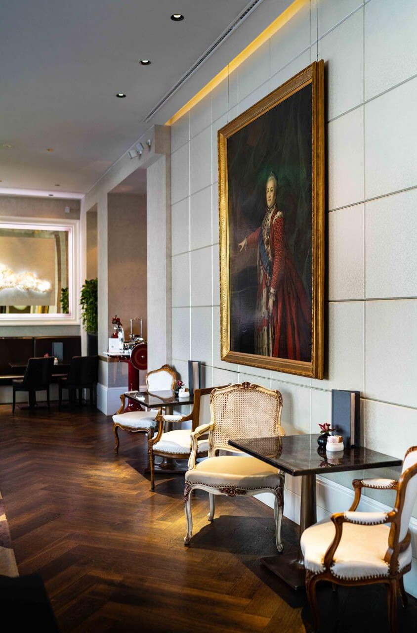 Elegant hotel lounge with classical furniture and a large portrait painting, radiating a sophisticated and serene ambiance.