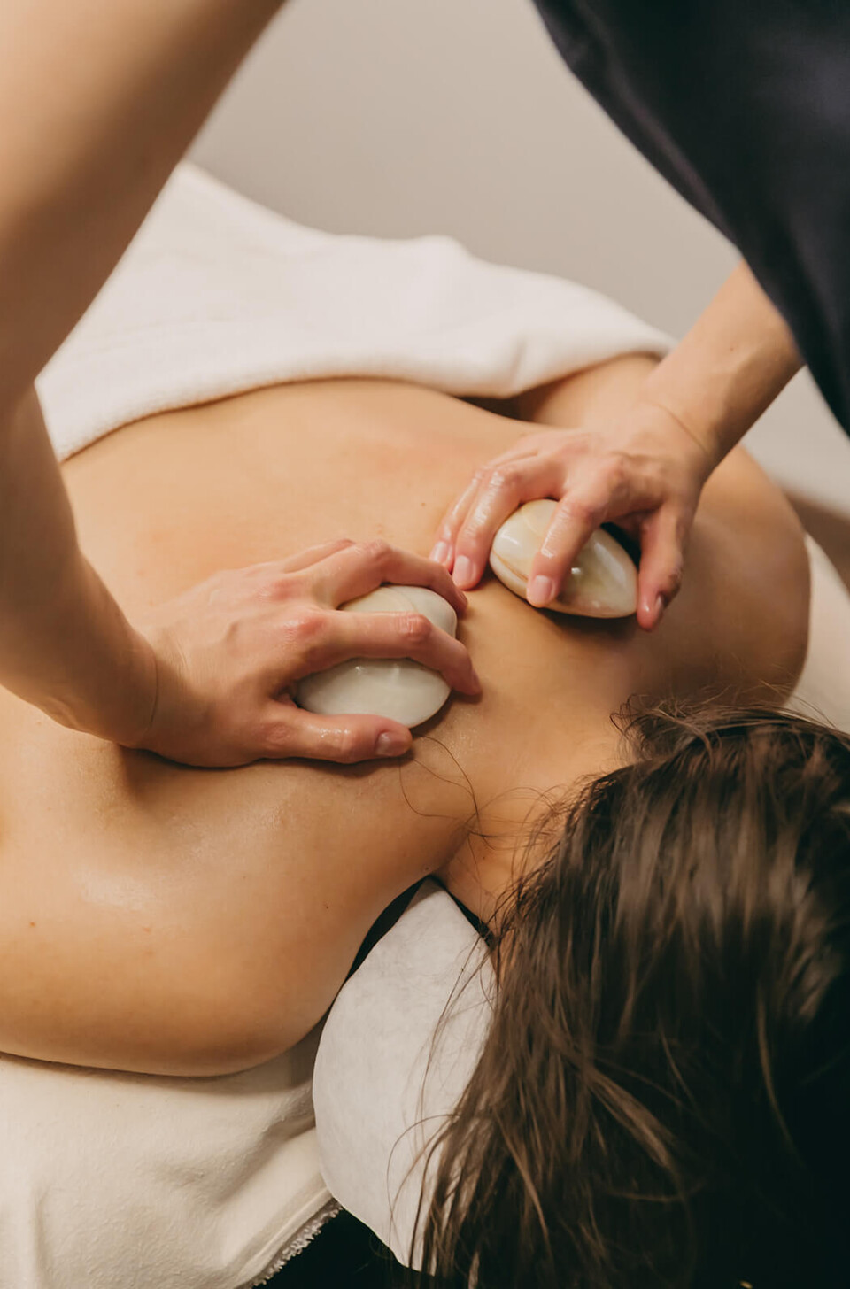 Relaxing massage session with a focus on back muscles using smooth white stones, evoking serenity for wellness industry.